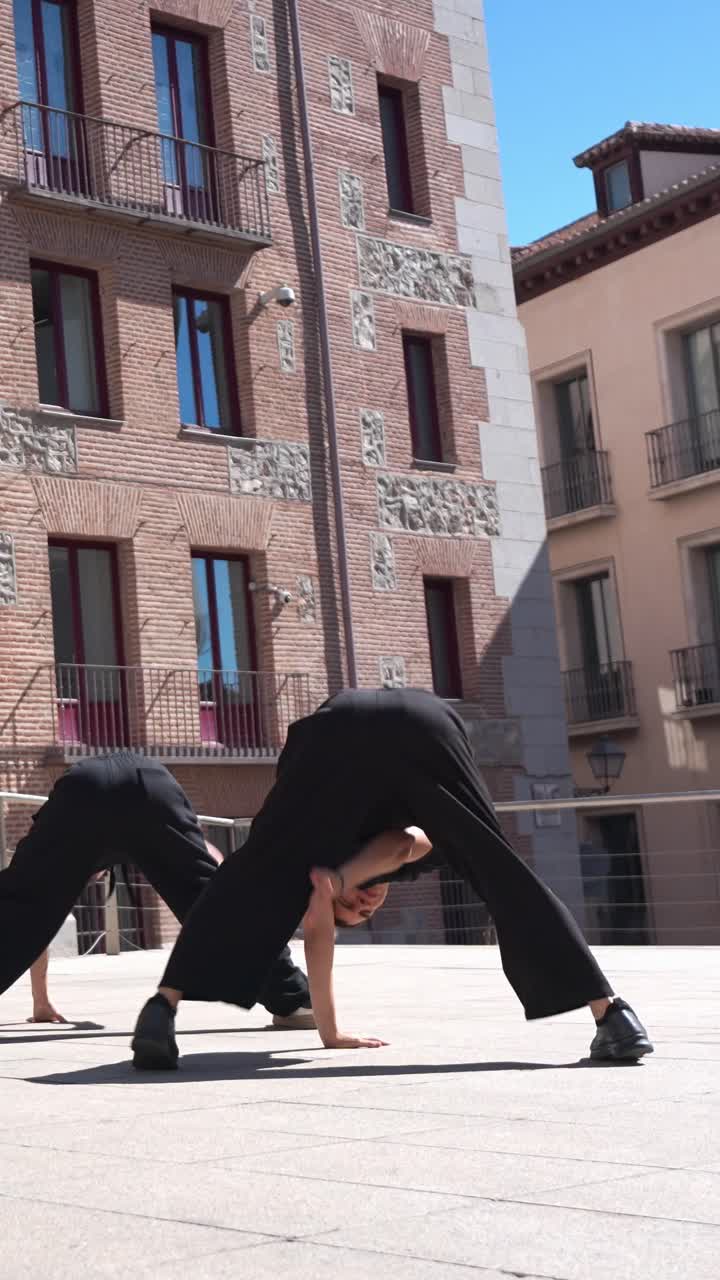 Giovani ballerini che eseguono una street dance energica in una piazza urbana.