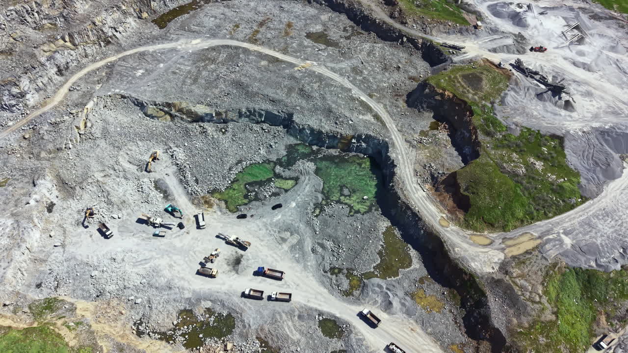 Granite quarry activity showing extraction site equipment and trucks in a working environment during daylight