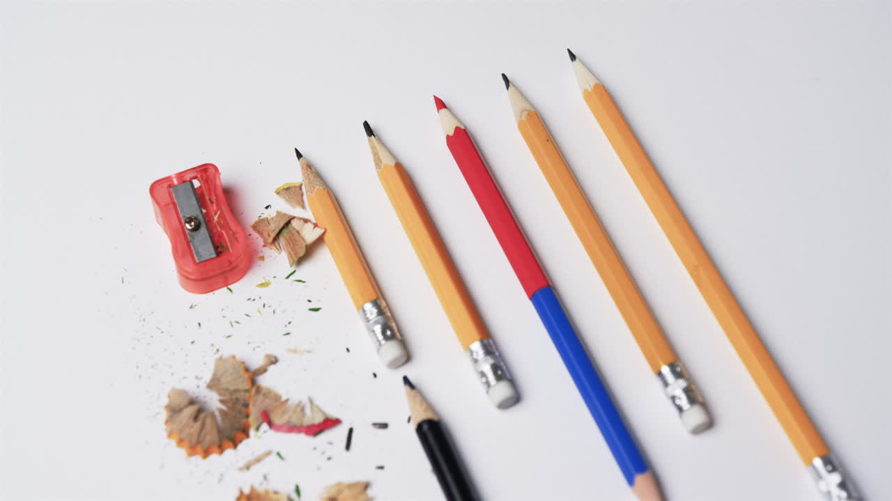 primer plano de lápices y afilador de lápiz sobre un fondo blanco, en cámara lenta