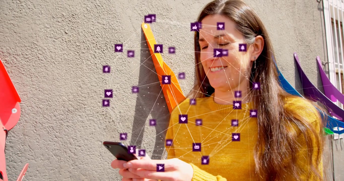 Animación de un globo de iconos digitales sobre una mujer caucásica usando un smartphone al aire libre.