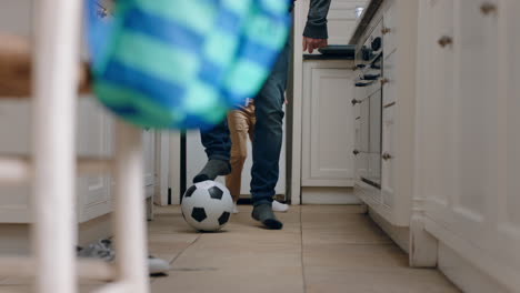 father and son playing with football in kitchen kicking soccer ball child enjoying game with dad at home