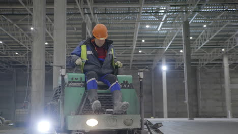 construction worker operating concrete grinder in a warehouse