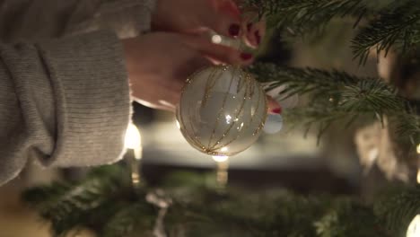 slow motion: woman with christmas ball in hand decorates christmas tree at night