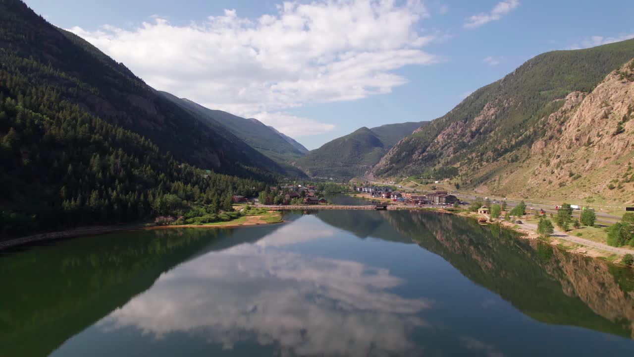 Aerial video of Georgetown Lake in Georgetown, Colorado. Camer flies low and slow over the lake showing the town and mountains in the background, with traffic driving on the right.
