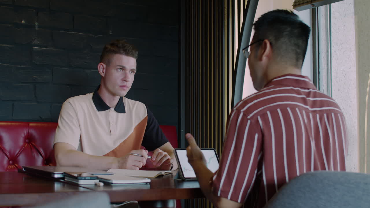 Entrepreneur Discussing Details of Project with Male Trader in Cafe