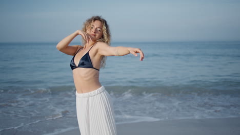 mujer serena bailando olas del océano mirando a la cámara con una sonrisa. bailarina de chica moviéndose