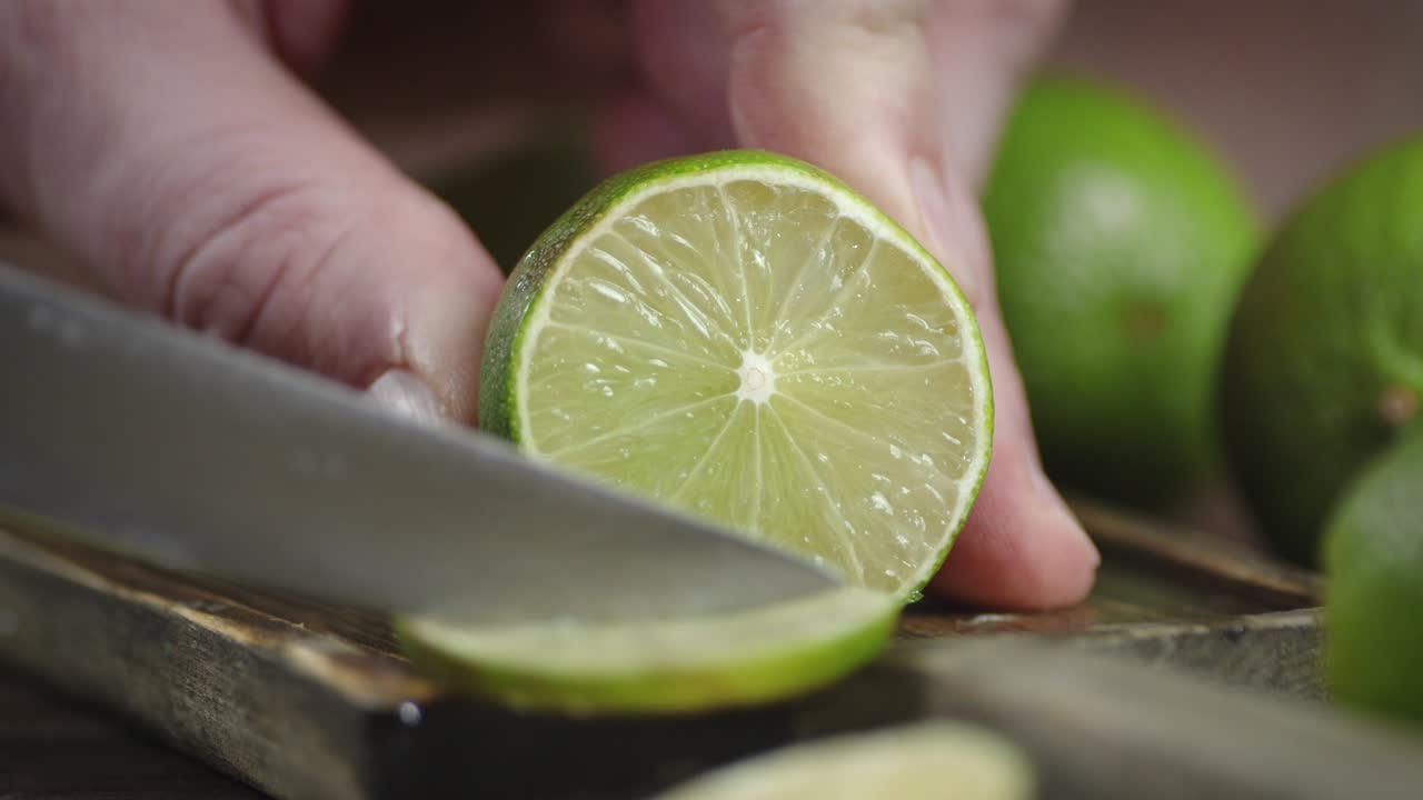 Male hand with a knife cut the lime.