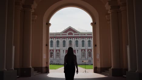 Jelgava-Palace-Gateway---unrecognizable-girl-in-dress-entering-courtyard---Back-view-wide-angle