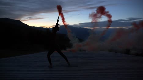 Zeitlupe:-Silhouette-Einer-Jungen-Frau,-Die-In-Der-Abenddämmerung-Auf-Einer-Plattform-Tanzt-Und-Lila-Rauch-Bengala-Flare-Hält