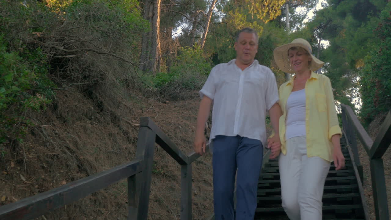 una pareja de ancianos caminando hacia la costa a través del bosque.