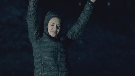 una dama bonita levanta las manos al cielo sonríe y disfruta de la fuerte lluvia.
