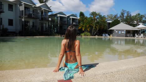 female model on a swimsuit leaning back at the edge of the pool in noosa holiday resort in australia