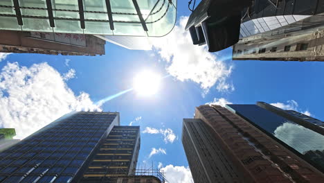 Blick-Nach-Oben-Ansicht-Von-Sonne-Und-Wolkenzeitraffer-Zwischen-Mong-Kok-Wolkenkratzern,-Hongkong