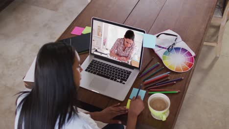 maestra caucásica usando una computadora portátil en una videollamada con una estudiante, tomando notas