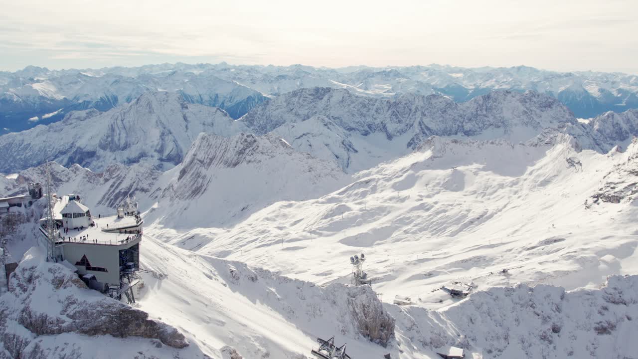 sorvolare l'impressionante edificio in cima alla Zugspitze nelle Alpi con la neve e la vista del ghiacciaio