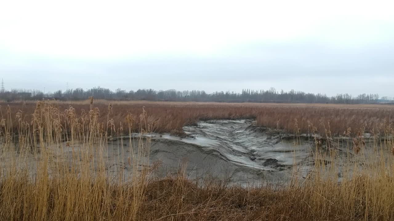 Aerial push in dried up wheat river bed muddy landscape cloudy dark swamp day