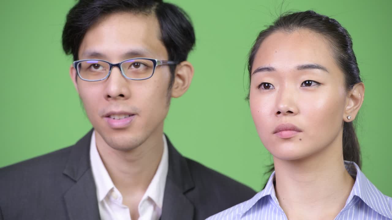 Young happy Asian business couple thinking together