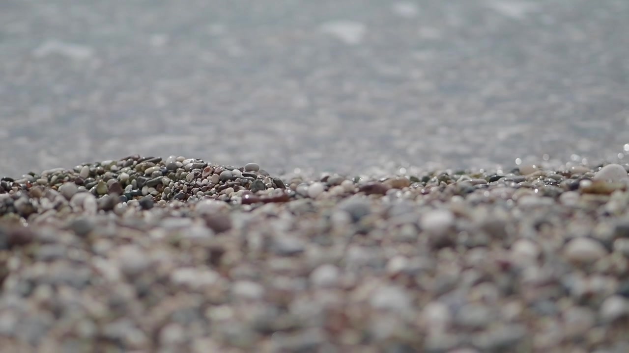 Close-up de praia de seixos com ondas suaves do oceano