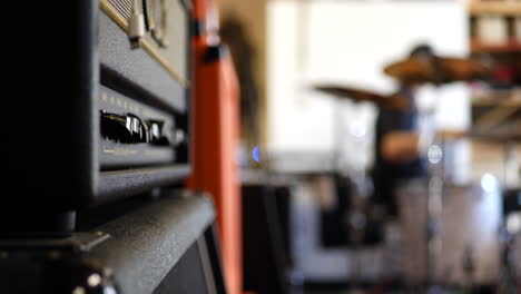 un amplificador de válvulas de guitarra eléctrica vintage con un baterista de banda de garaje de rock and roll en cámara lenta de fondo