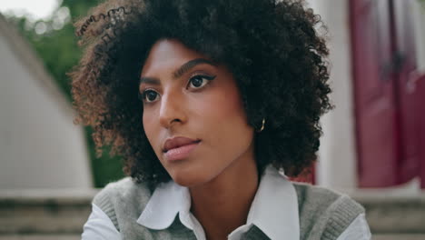 beautiful woman face brown skin closeup. african girl sitting stairs city street