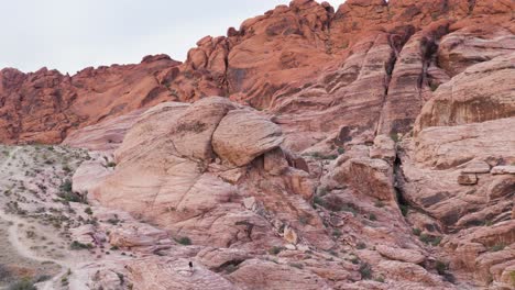 Tiny-man-running-in-rocky-landscape-in-Red-Rock-Canyon-National-Conservation-Area-in-Nevada,-USA-in-slow-motion