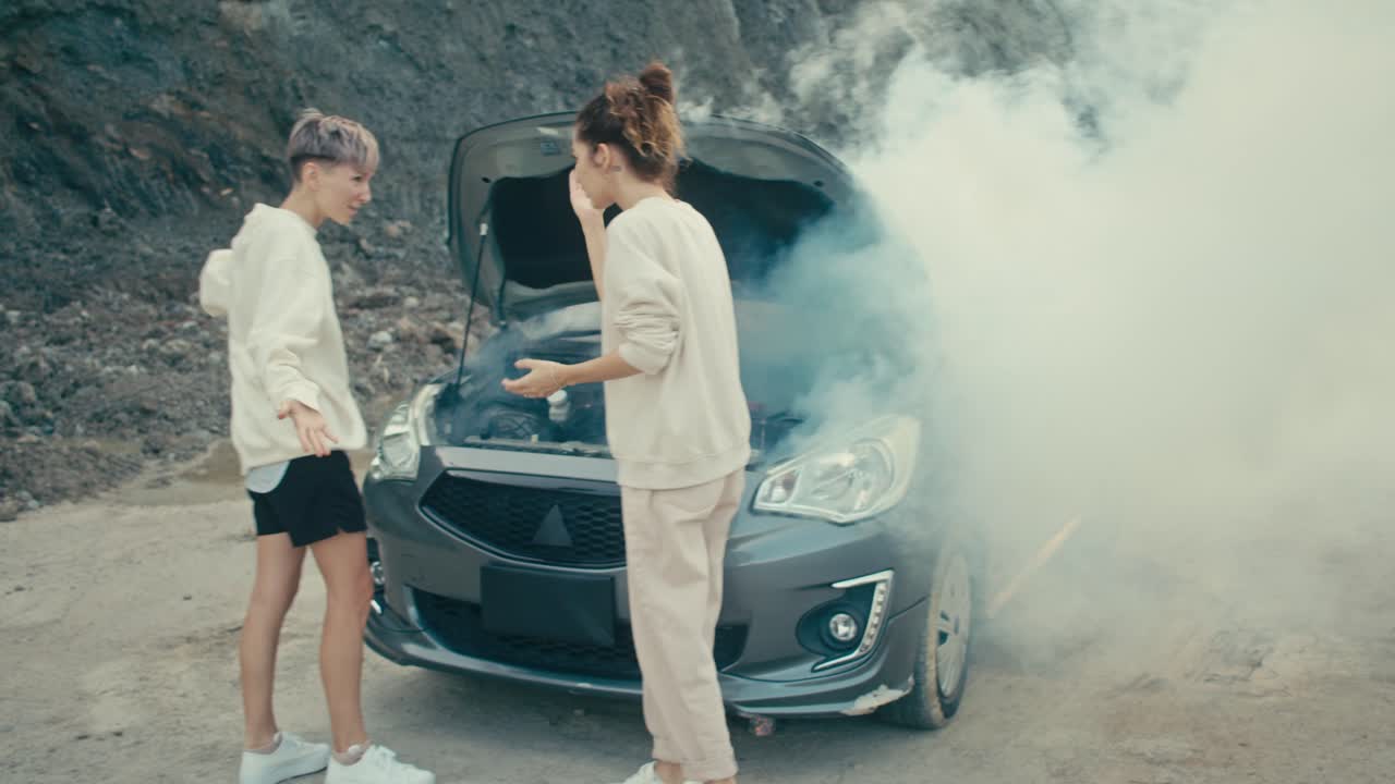 Two Women Dealing With a Smoking Car Engine on the Roadside