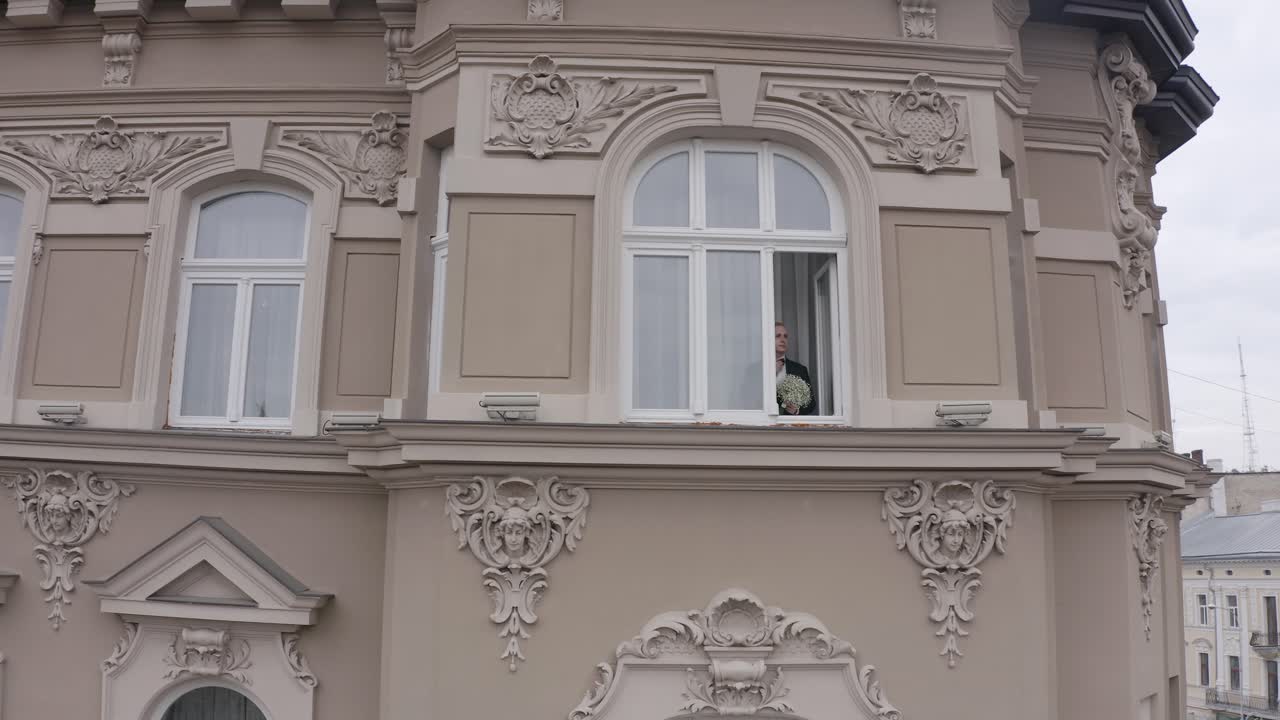 vista aérea del novio con estilo el hombre se queda en la ventana en casa se prepara antes de la fecha o la reunión con la novia