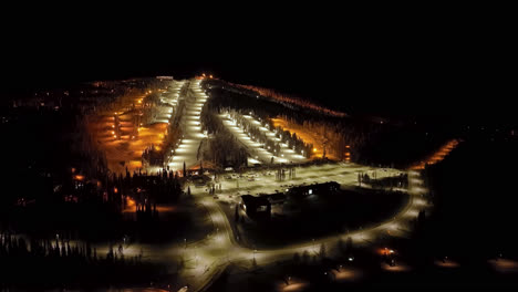 Aerial-view-around-the-illuminated-slopes-of-Syote,-winter-night-in-Finland