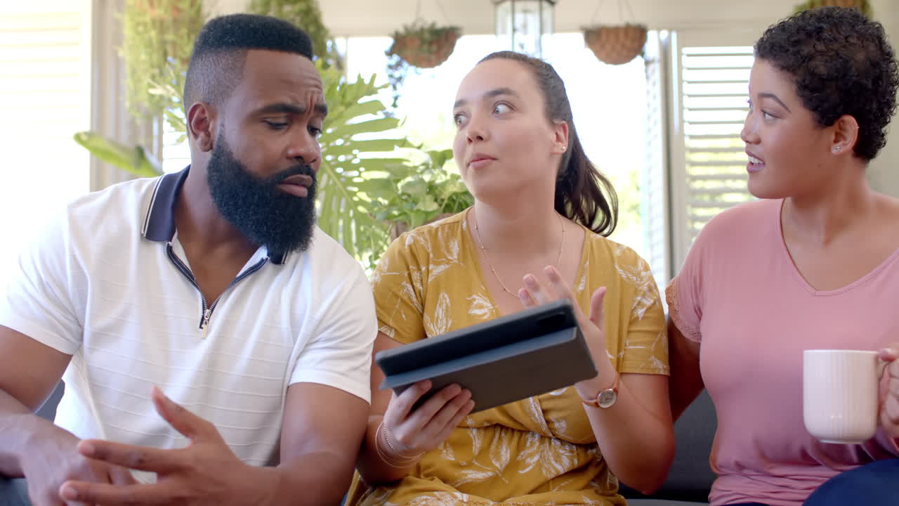 Using tablet and discussing, diverse group of friends sitting together