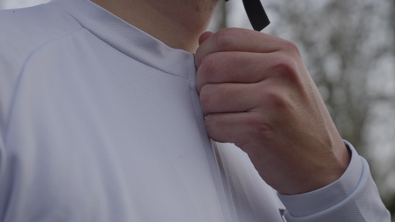 Close up of hand pulling zipper on white cycling jacket outdoor