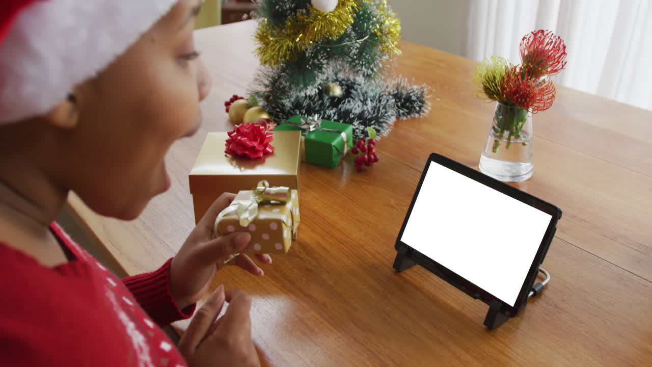 mujer afroamericana en sombrero de santa haciendo llamada de video de navidad portátil, con espacio de copia en la pantalla