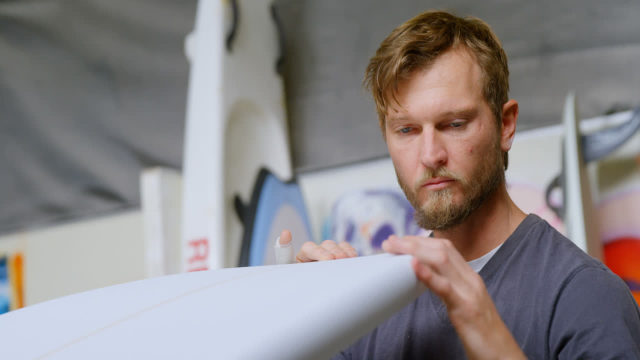 Man examining a surfboard 4k