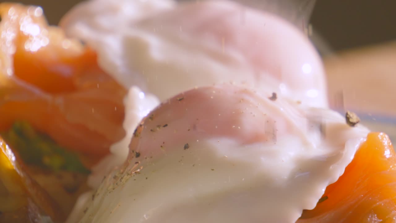 Ultra Slow Motion of Pepper Falling on Breakfast of Avocado Crumpet with Smoked Salmon Topped with Poached Egg. Morning High Protein Healthy Stylish Food Brunch Footage 4K.