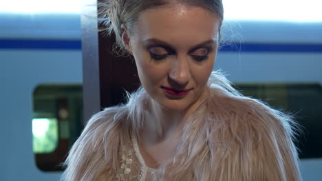 modelo glamorosa sentada en la estación de tren con vestido de novia, inclinada hacia arriba