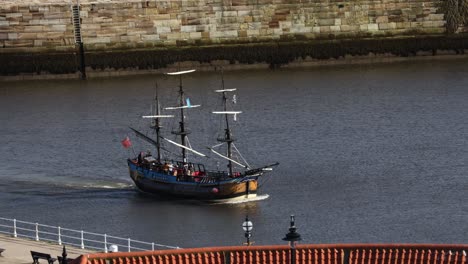 hand-held tracking shot of a pirate ship sailing into whitby harbour