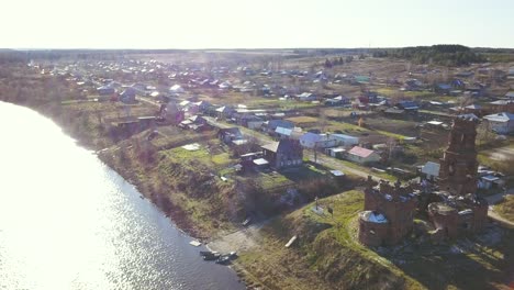 aerial view of a russian village by a river with an abandoned church