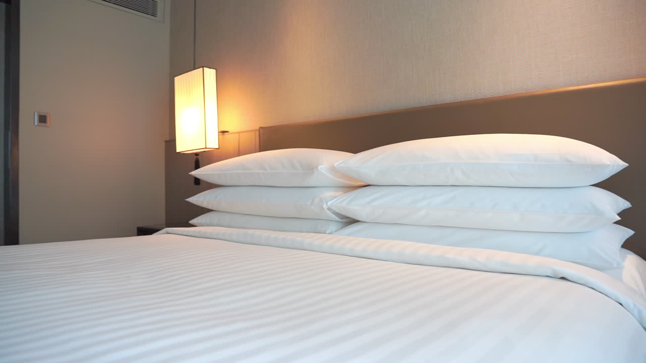 cómoda cama doble tamaño king con seis almohadas y lámpara de pared