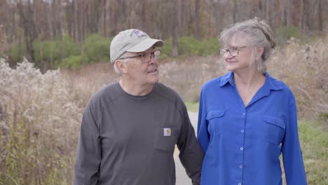 una pareja de ancianos caminando por el sendero a través del parque y sonriendo