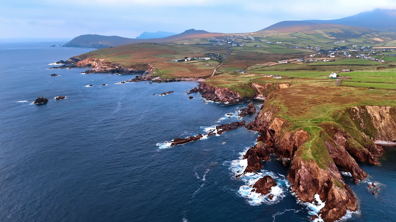 Approaching rocky shores of Northern Ireland from above the waterscape. Aerial perspective on the village located nearby the Atlantic Ocean coast.