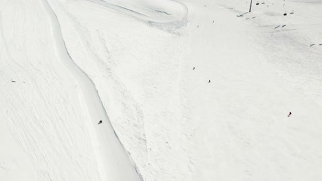 Drone-footage-of-multiple-people-participating-in-winter-sports---Sledging,-Snow-Boarding-and-Skiing-in-the-Alpine-slopes-of-Zugspitze,-Germany