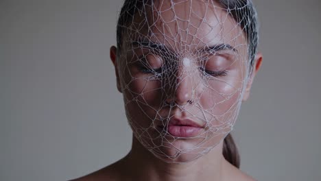 montage of a young woman with closed eyes and a white net covering her face, possibly symbolizing introspection, vulnerability, or confinement