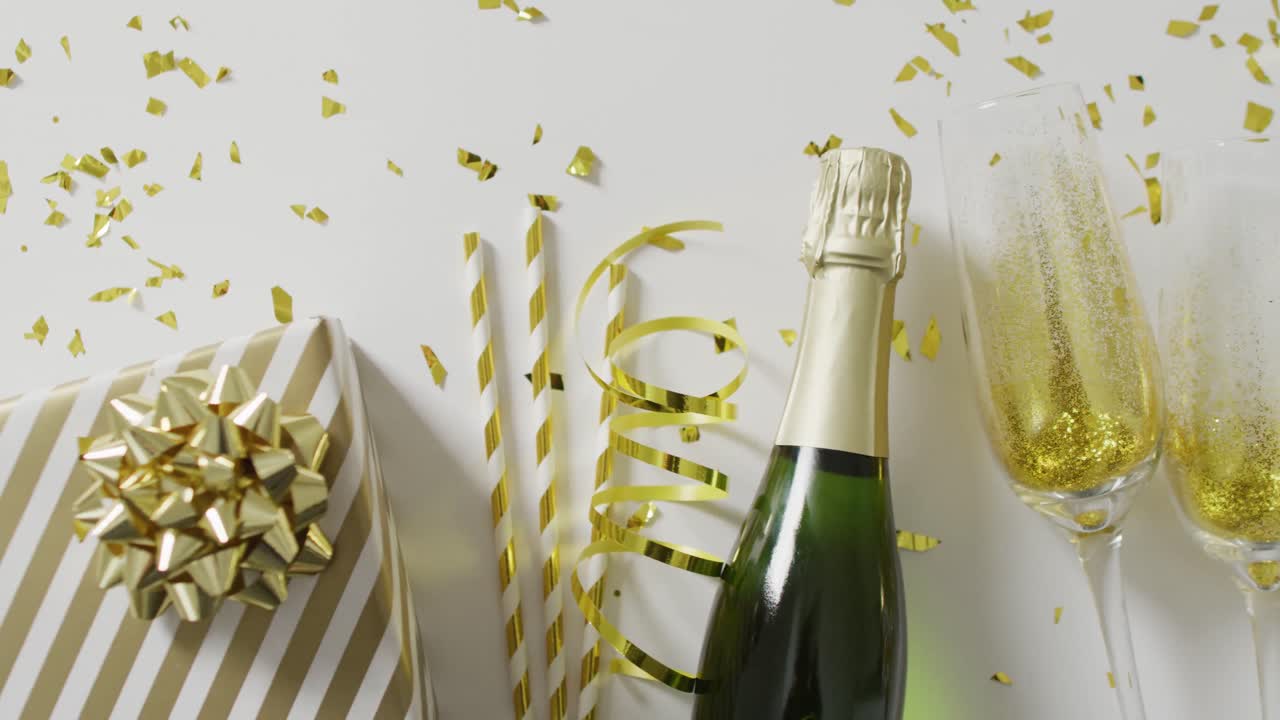Video di bottiglia di champagne, bicchieri e regali con stelle filanti dorate e coriandoli su bianco