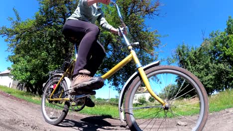 young woman riding vintage bicycle along a rural road in a village
