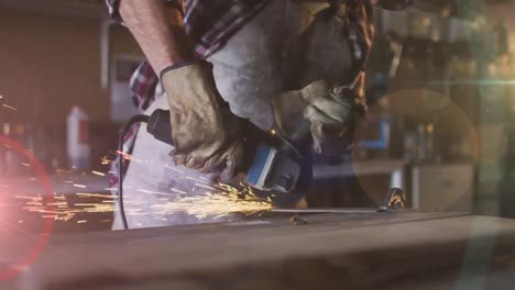 Animation-of-glowing-light-over-caucasian-man-using-grinder-in-workshop