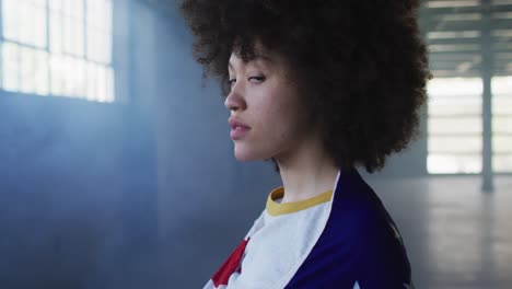 Portrait-of-african-american-woman-with-american-flag-on-her-back-in-empty-parking-garage