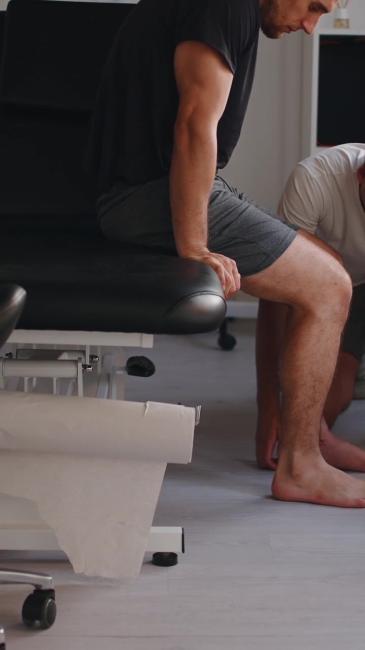 Physical Therapist Examining Patient's Leg in Clinic