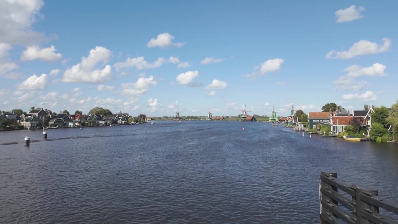 Vindmøller langs en flodbred under en lys himmel, Zaanse Schans.