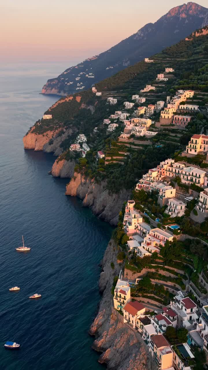 Aerial view of a coastal town at sunset, showcasing terraced houses on cliffs