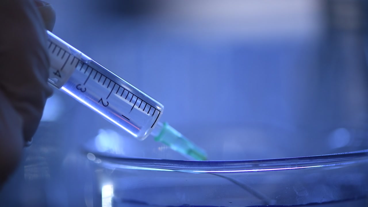 Gros plan d'une seringue aspirant un liquide clair dans un laboratoire