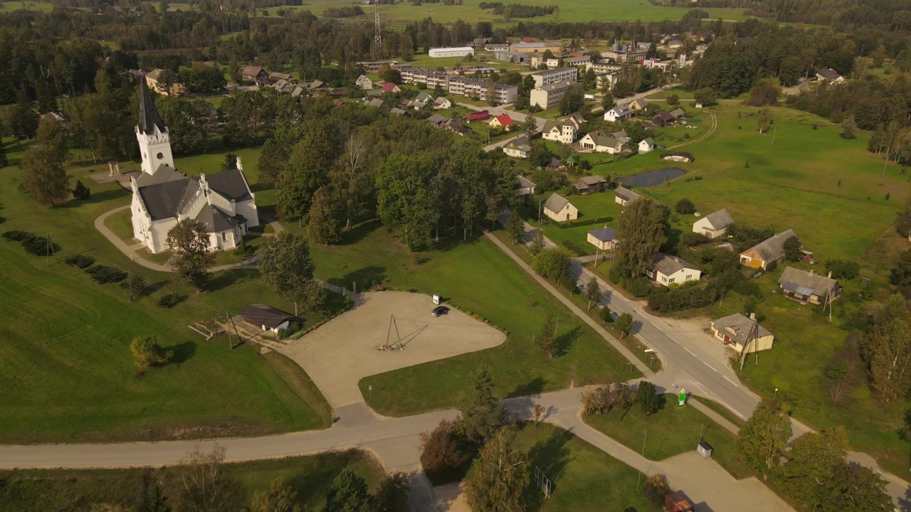 Dronekuva Pyhän Tuomaan evankelis-luterilaisesta kirkosta Jaunpiebalgassa, kuvattuna kirkkaana päivänä. Kirkko erottuu kaupungin rakennusten joukosta, vehreyden ja katujen ympäröimänä